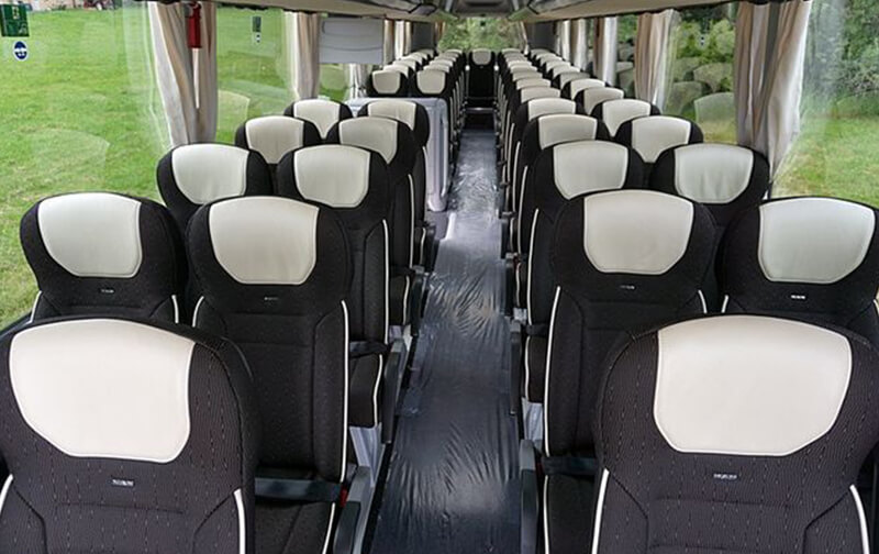 Innenraum eines Reisebusses mit verstellbaren Sitzen und Mittelgang